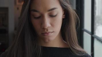 Close up of young mixed race woman looking down, lifts head and hands, holding face mask, puts on face mask, adjusts it, looks in lens video