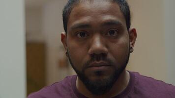 Close up of black man, looking down, lifts head, looking in camera lens video