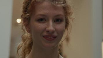 Close up di giovane donna bianca in piedi nel corridoio, sorridendo all'obiettivo della fotocamera video
