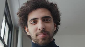 Close up and slow motion of young Middle Eastern man, looking into camera lens, bottom up shot, eyes following camera, smiling eyes and mouth video