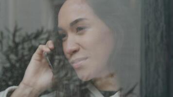 Close up of young Middle Eastern man standing in front of house, calling young mixed race woman, standing behind window video