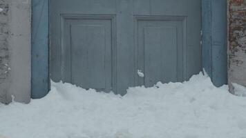 Medium shot of lower part of light blue door, medium blue door frames and walls, piled up snow against door, snow in foreground video