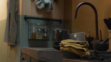 Close up of sink and part of kitchen counter with tap, cups, saucers, kitchen towel, mortar, and part of furnace in foreground video