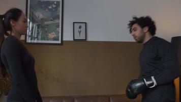 jonge man uit het Midden-Oosten met bokshandschoenen stoten door de handen van een vrouw van gemengd ras, handen voor haar, laatste stoot, ze lachen video