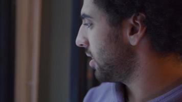 ung man från Mellanöstern rör huvudet och tittar på fönstret medan han pratar video