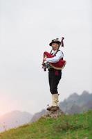 Hombre usando una gaita, un instrumento tradicional del norte de Italia similar a los instrumentos escoceses y la gaita gallega foto