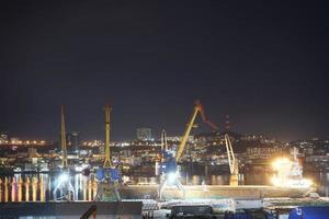 El paisaje nocturno de la ciudad con vistas a un puerto y al horizonte de fondo en Vladivostok, Rusia foto