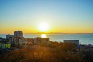 Cityscape next to a body of water with colorful sunset in Vladivostok, Russia photo