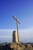 A golden metal cross on a rocky hill with a cloudy blue sky in Vladivostok, Russia photo