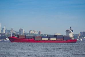 Seascape with a red container ship and city skyline in the background in Vladivostok, Russia photo