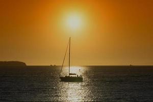 Silueta de un yate en el agua con una puesta de sol de color naranja brillante en Vladivostok, Rusia foto