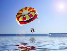 People parasailing on a body of water with clear blue sky photo
