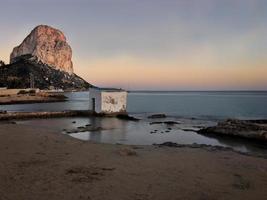 Playa mediterránea al atardecer con el peñón de fondo en Calpe, Alicante foto