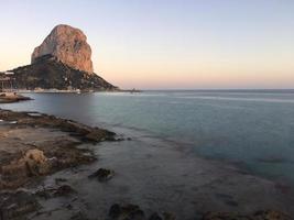 Playa mediterránea al atardecer con el peñón de fondo en Calpe, Alicante foto