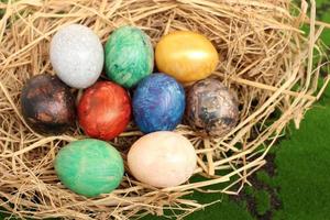 Straw basket with Easter eggs on a grass background