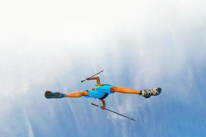 Young man athlete makes a jump with nordic walking sticks photo