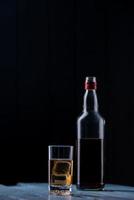 Bodegón con vidrio y botella de alcohol en la mesa de madera foto