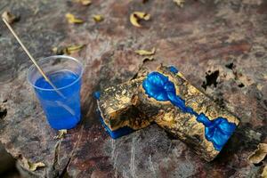 Casting blue epoxy resin on burl wood cubes on an old wooden table