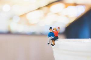 Pareja en miniatura sentada en una taza, concepto del día de San Valentín foto