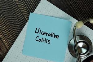 Ulcerative Colitis written on sticky note isolated on wooden table photo