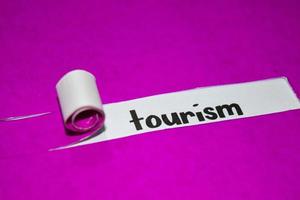 Tourism text, Inspiration, Motivation and business concept on purple torn paper photo