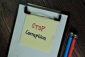 Stop Corruption written on sticky note isolated on wooden table photo