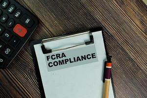 FCRA Compliance written on paperwork isolated on wooden table photo