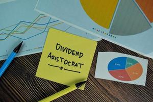 Dividend Aristocrat written on sticky note isolated on wooden table photo