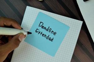 Deadline Extended written on sticky note isolated on wooden table photo