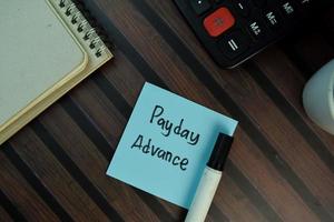 Payday Advance written on sticky note isolated on wooden table photo