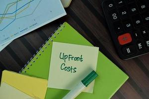 Upfront Costs written on sticky note isolated on wooden table photo