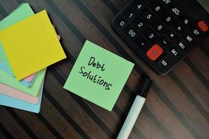 Debt Solution written on sticky note isolated on wooden table photo