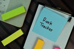 Rank Tracker written on sticky note isolated on wooden table photo