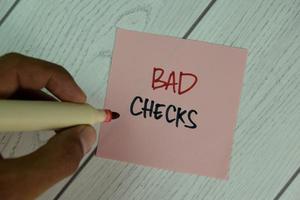 Bad Checks written on sticky note isolated on wooden table photo