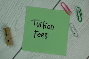 Tuition Fees written on sticky note isolated on wooden table photo