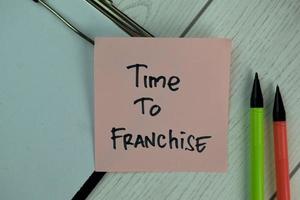 Time To Franchise written on sticky note isolated on wooden table photo