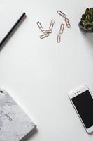 Desk with notebook, phone, pencil, plant and paper clip photo