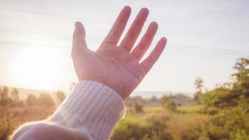 Soft focus of woman's hand reaching towards nature and sky photo
