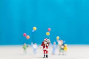 Papá Noel en miniatura y niños sosteniendo globos, feliz navidad y feliz año nuevo concepto foto