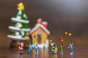 Papá Noel en miniatura y niños sosteniendo globos, feliz navidad y feliz año nuevo concepto foto