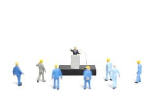 Miniature people listening to a politician speaking during an election rally