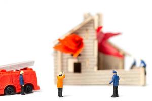 Miniature firefighters taking care of a fire emergency at a wooden house photo