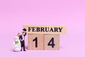 Miniature bride and groom on a pink background, Valentine's Day and wedding concept photo