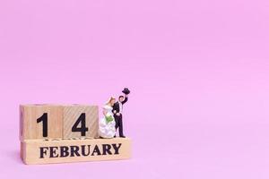 Miniature bride and groom on a pink background, Valentine's Day and wedding concept photo