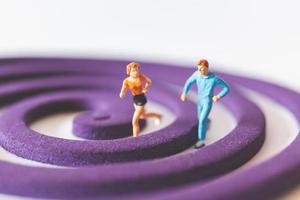 Pareja en miniatura corriendo sobre un campo circular púrpura foto