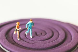 Miniature couple running on a purple circular field photo