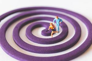 Miniature couple running on a purple circular field photo