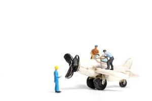 Miniature workers repairing a toy airplane on a white background photo