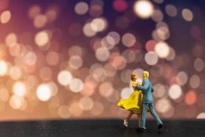 Pareja en miniatura bailando con un fondo bokeh, concepto de día de San Valentín foto