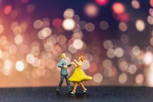 Pareja en miniatura bailando con un fondo bokeh, concepto de día de San Valentín foto